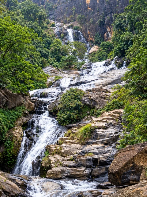 Realistic re-creation of Ravana Falls cascading over stepped rock surrounded by forest near Ella